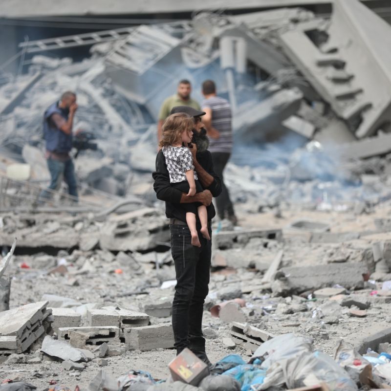 A person holds a young child amid rubble in Gaza. Courtesy of MSF