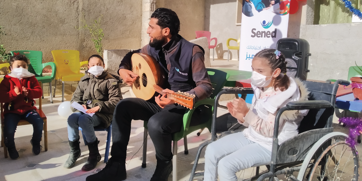 a man plays a guitar and sings with a group of youth